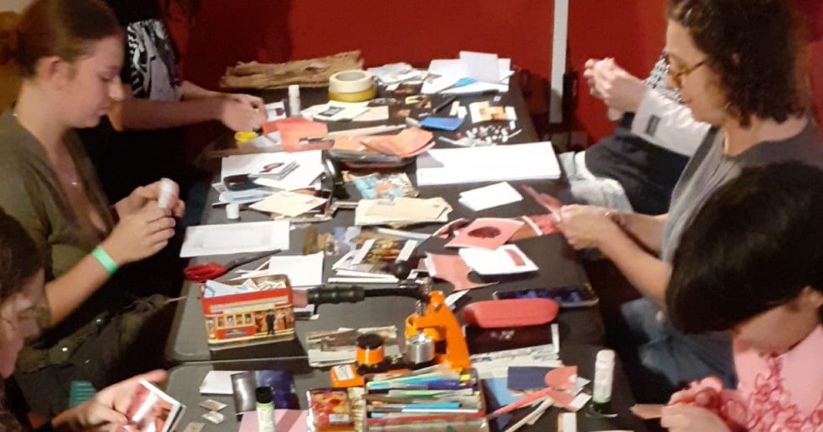 Group of people sitting on a table making zines