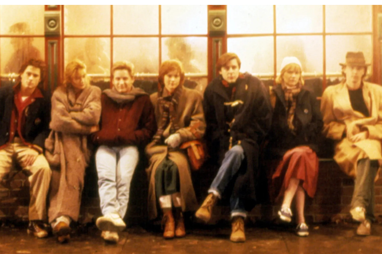 Group of young adults sit in a row outside a bar