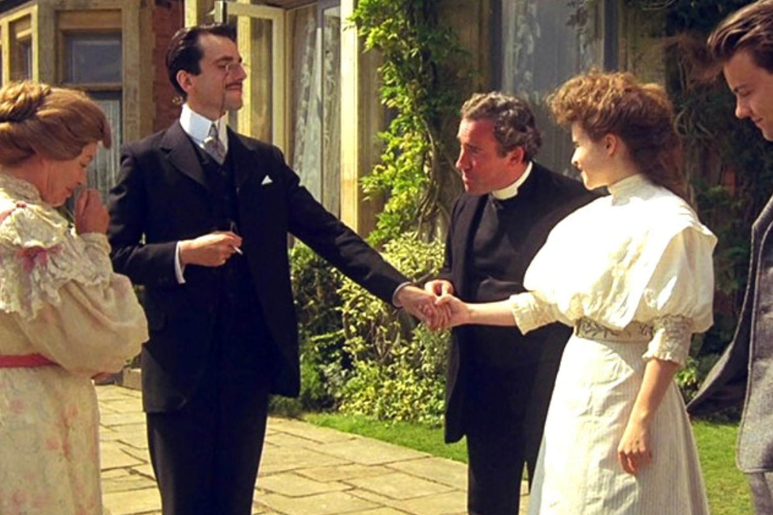 Group of people in Victorian dress standing outside in a neat garden